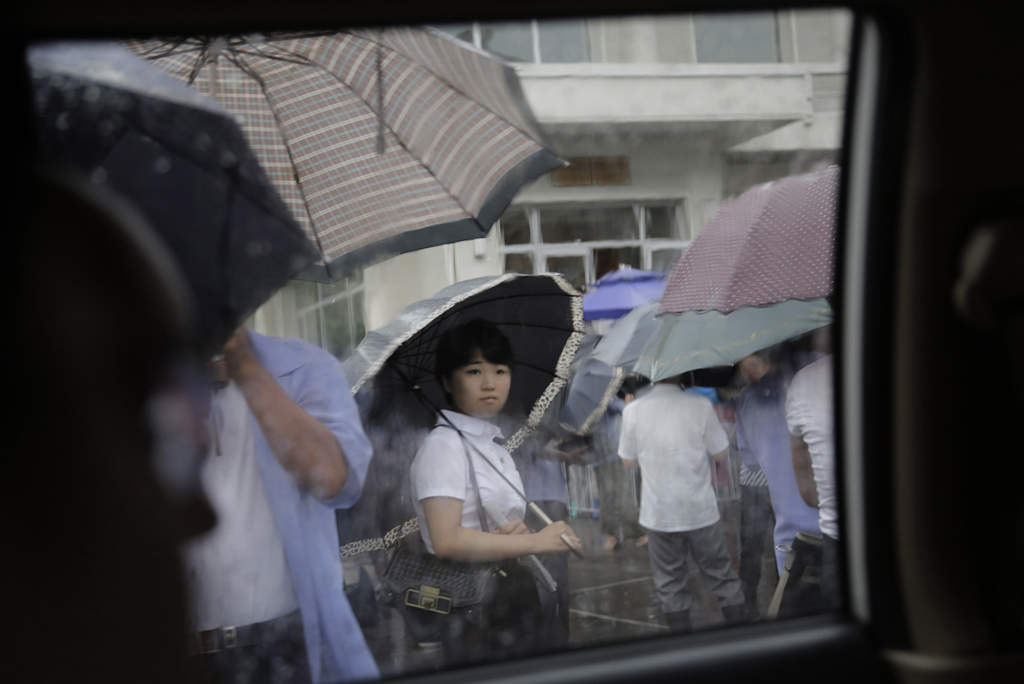 En kvinna väntar i regnet utanför en restaurang, den 25 juli 2015. Foto: AP