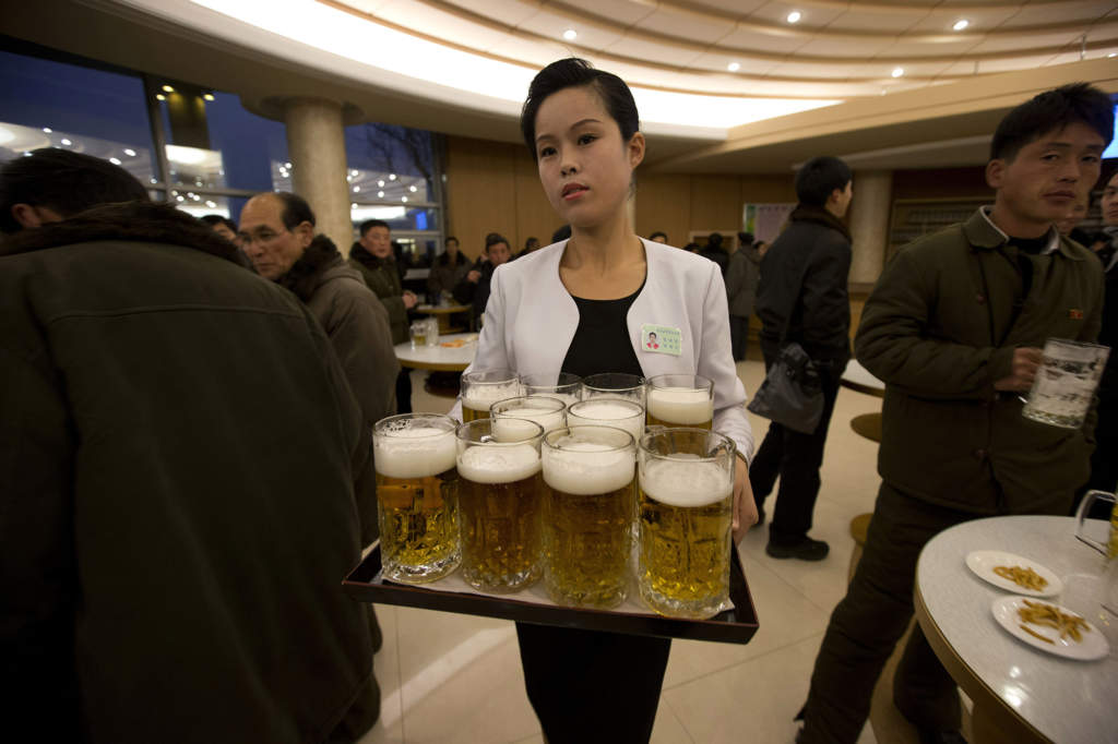 En servitris bär en bricka med öl på Mansugyo läskrestaurang i Pyongyang, den 20 december 2012. En ombyggnad av den klassiska restaurangen – som erbjuder sju olika sorters öl – beordrades av Kim Jong-Un själv. Foto: AP